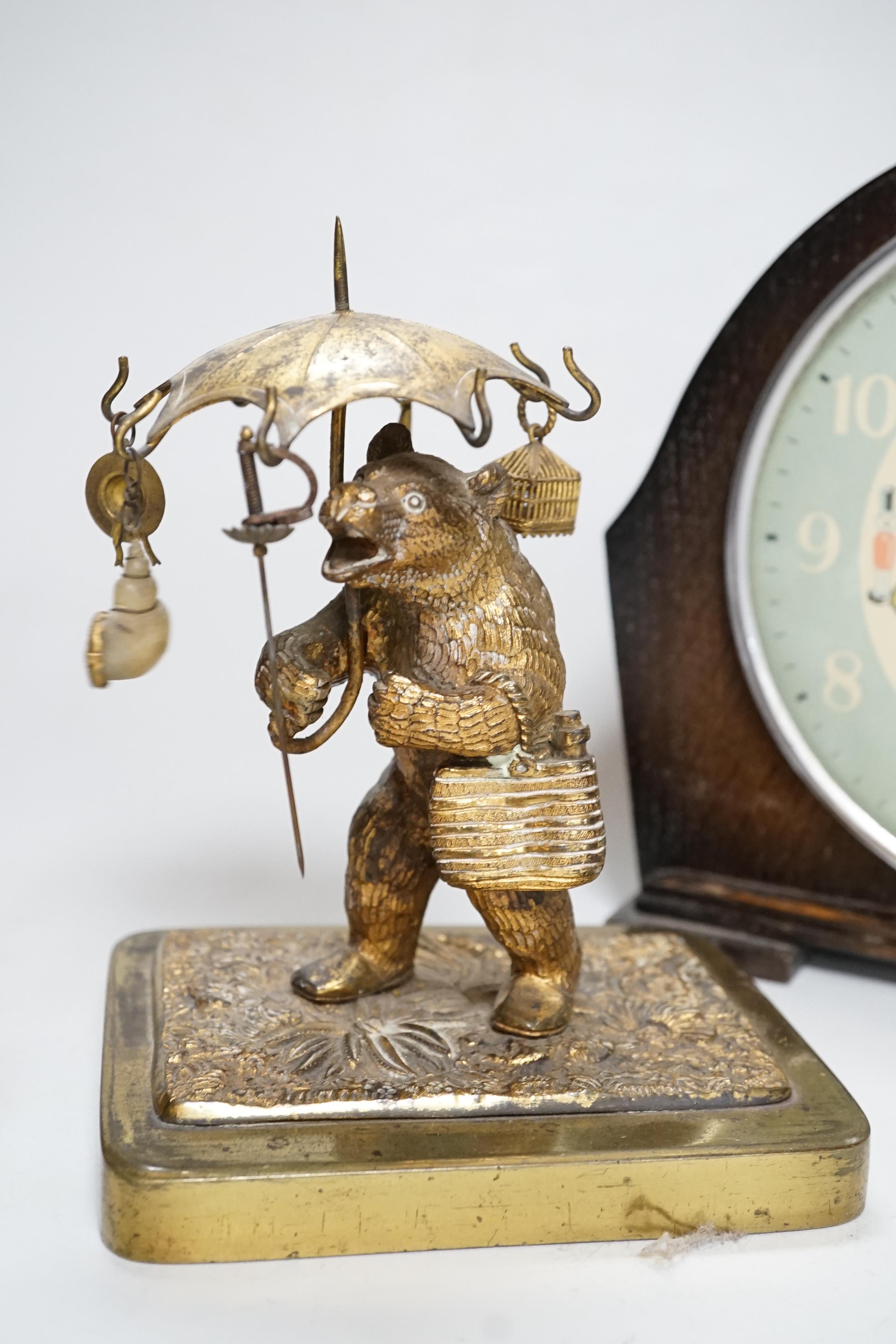 A Smith teddy bear clock, a seated metal bear holding a pocket watch, a metal standing bear with parasol and a German metal bear calendar